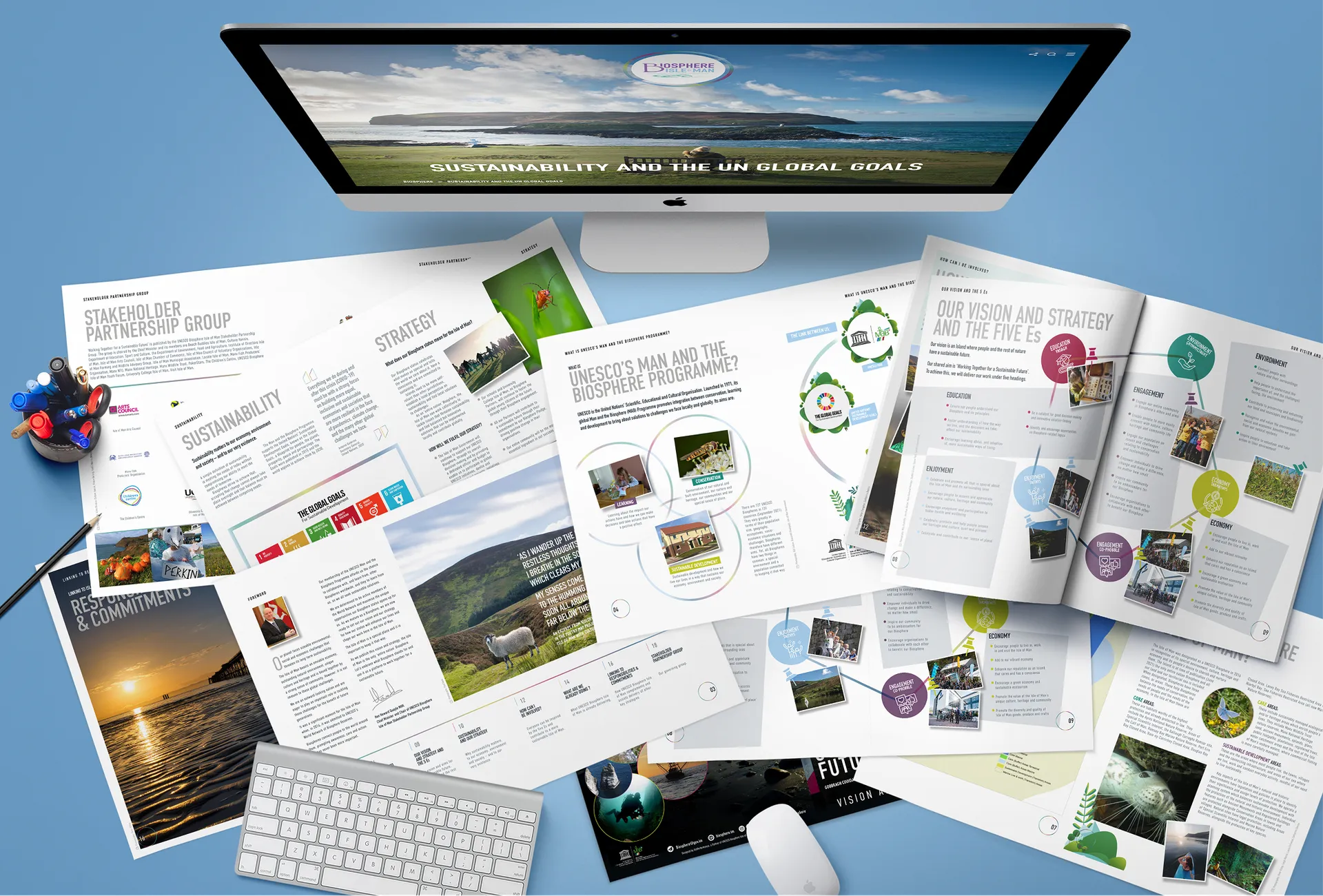 Biosphere Isle of Man website and printed Vision and Strategy publication shown together, with a desktop screen displaying the sustainability and UN global goals page and multiple open document spreads covering strategy, stakeholder groups and the five Es framework, designed by DotPerformance